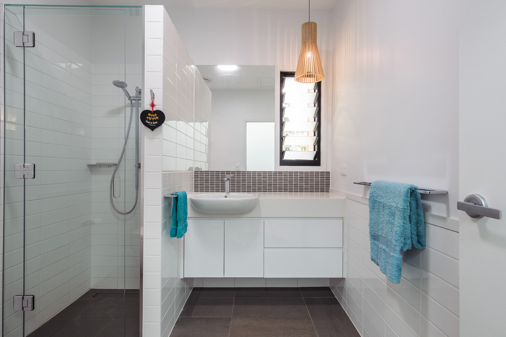 Contemporary bathroom in Brisbane with grey tiles and white cabinets.