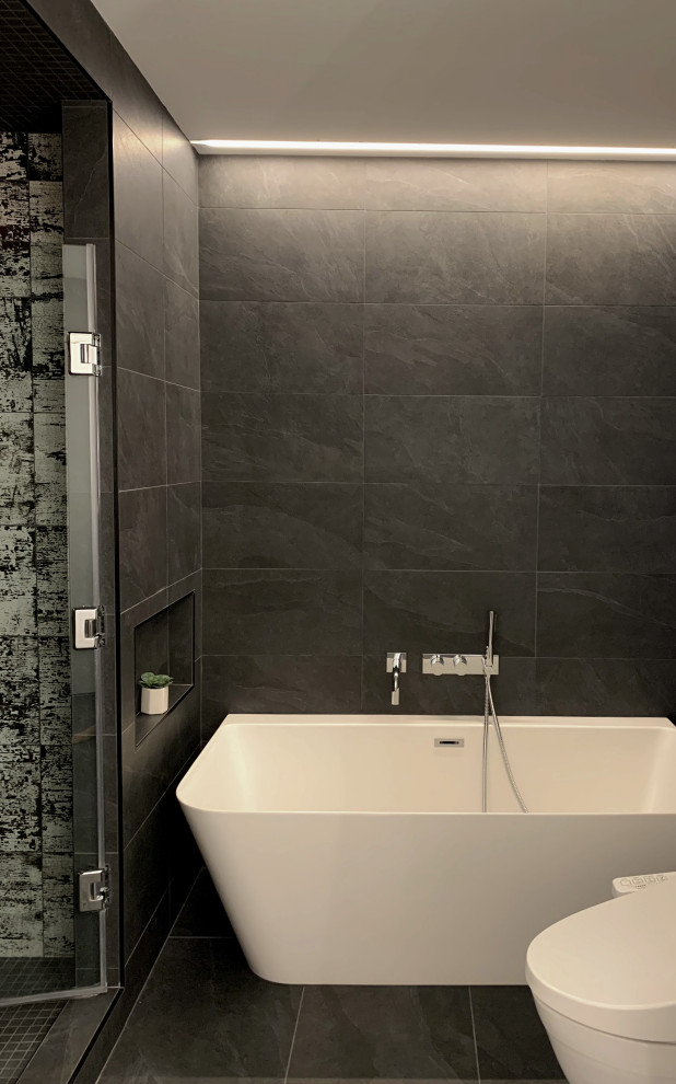 Modern inredning av ett stort vit vitt en-suite badrum, med släta luckor, ett fristående badkar, en dusch i en alkov, en toalettstol med hel cisternkåpa, grå kakel, porslinskakel, klinkergolv i porslin, ett integrerad handfat, bänkskiva i akrylsten, grått golv och dusch med gångjärnsdörr