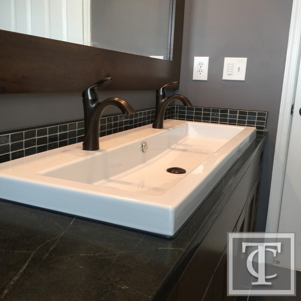 Photo of a medium sized eclectic family bathroom in Baltimore with recessed-panel cabinets, medium wood cabinets, a double shower, a two-piece toilet, green tiles, glass tiles, grey walls, ceramic flooring, a trough sink and soapstone worktops.