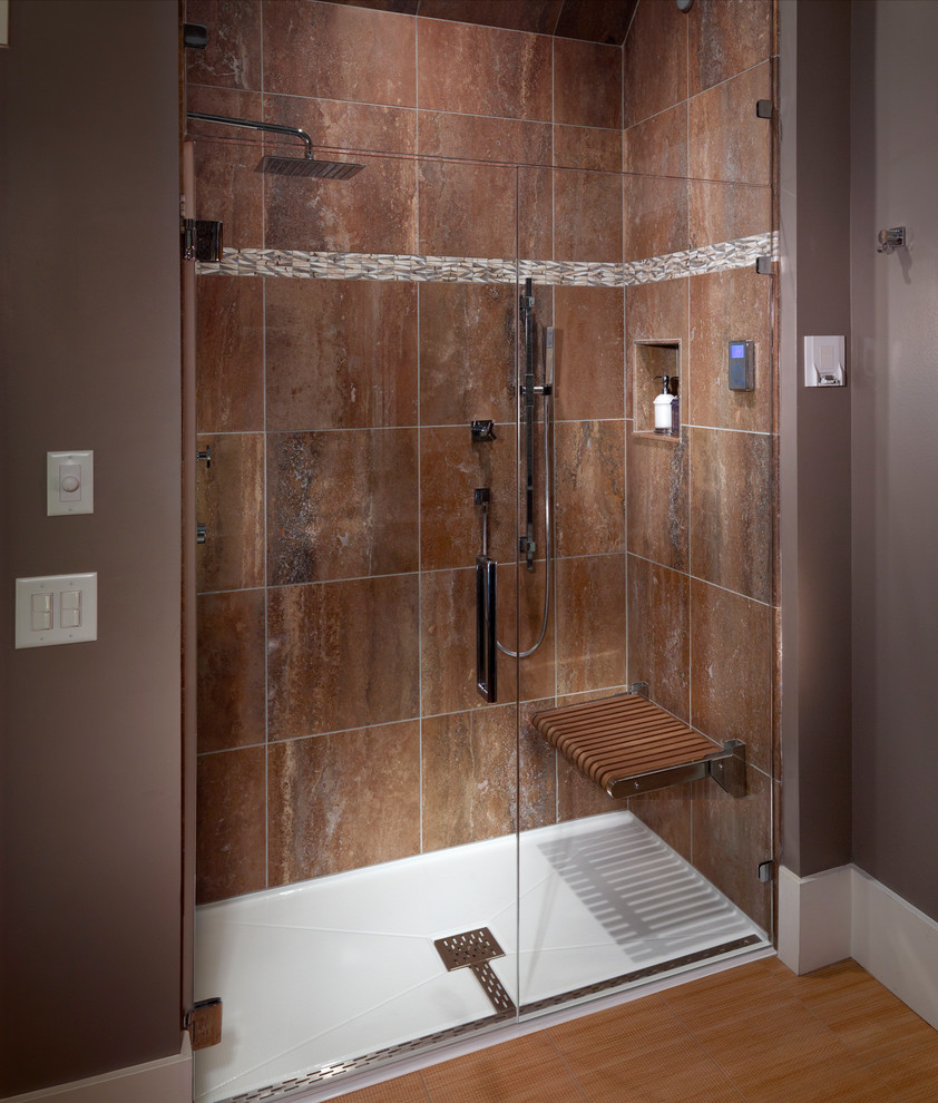 Bild på ett badrum, med en dusch i en alkov, brun kakel, vinylgolv och bruna väggar
