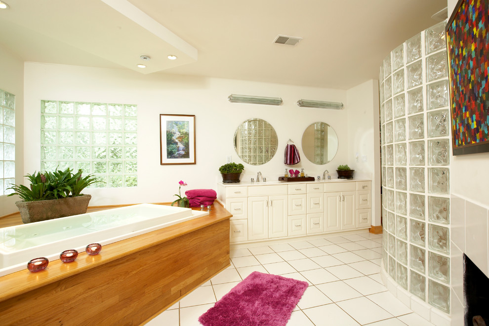 Foto di una stanza da bagno design con ante bianche, vasca da incasso e piastrelle bianche
