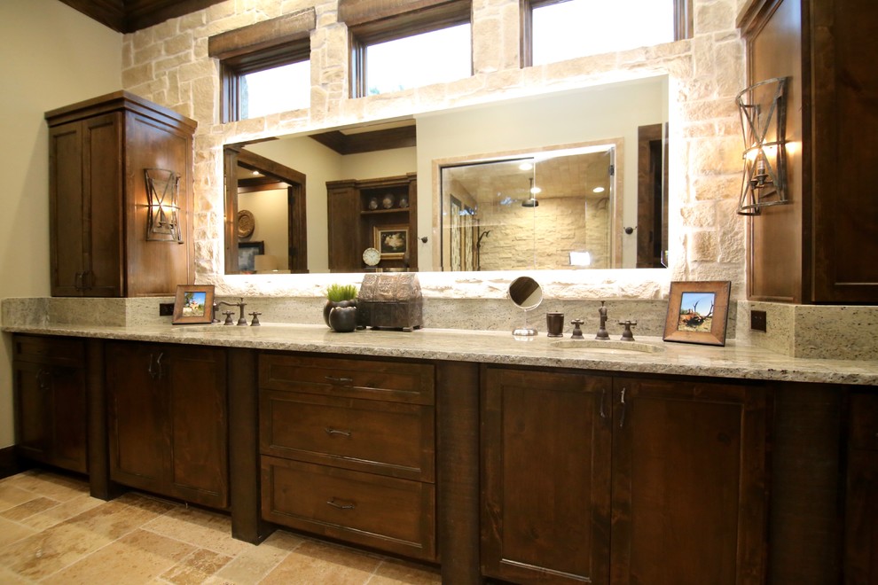 Alcove shower - large rustic master stone tile travertine floor and beige floor alcove shower idea in Dallas with shaker cabinets, dark wood cabinets, an undermount sink, granite countertops, beige walls and a hinged shower door