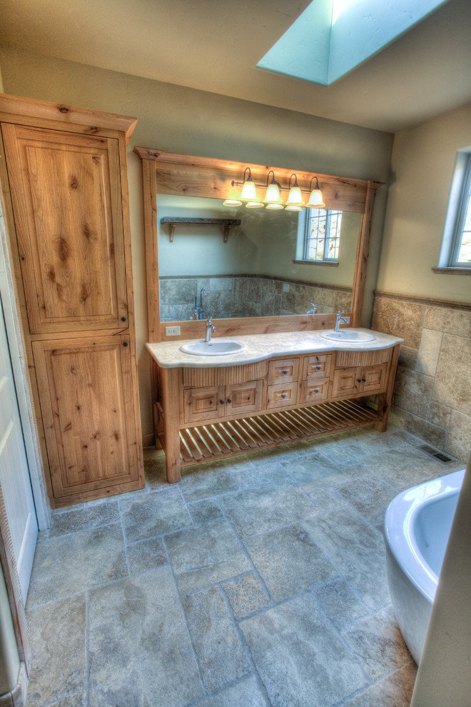 Cette photo montre une grande salle de bain principale montagne en bois clair avec un lavabo posé, un placard avec porte à panneau surélevé, un plan de toilette en granite, un carrelage multicolore, un carrelage de pierre, un mur beige, une baignoire indépendante, WC séparés et un sol en ardoise.