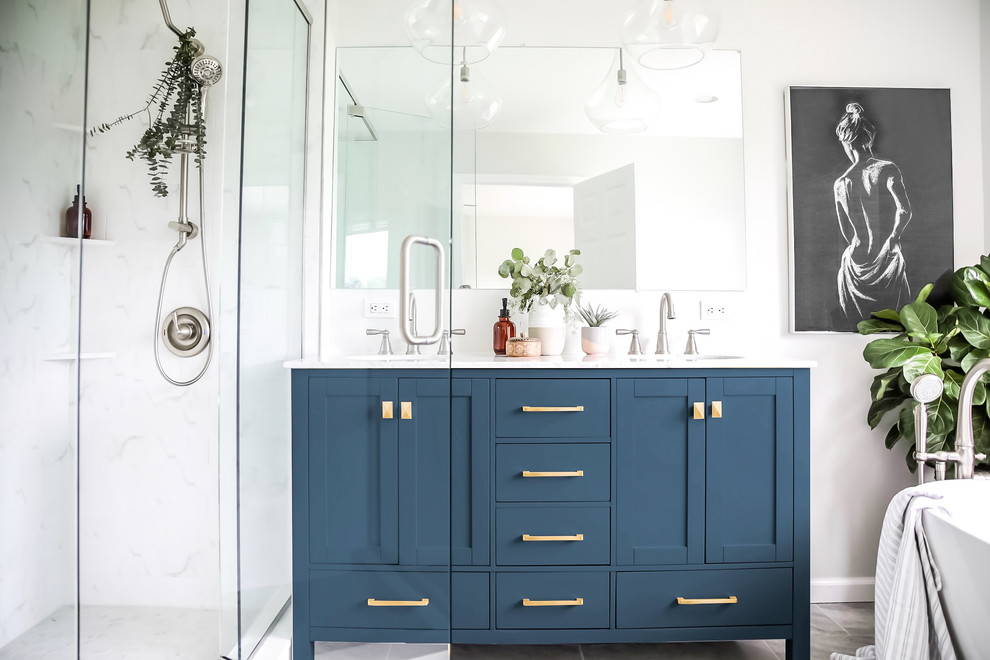 Пример оригинального дизайна: главная ванная комната среднего размера в стиле неоклассика (современная классика) с синими фасадами, отдельно стоящей ванной, угловым душем, раздельным унитазом, белой плиткой, мраморной плиткой, серыми стенами, полом из керамогранита, врезной раковиной, мраморной столешницей, серым полом, душем с распашными дверями, желтой столешницей и фасадами в стиле шейкер