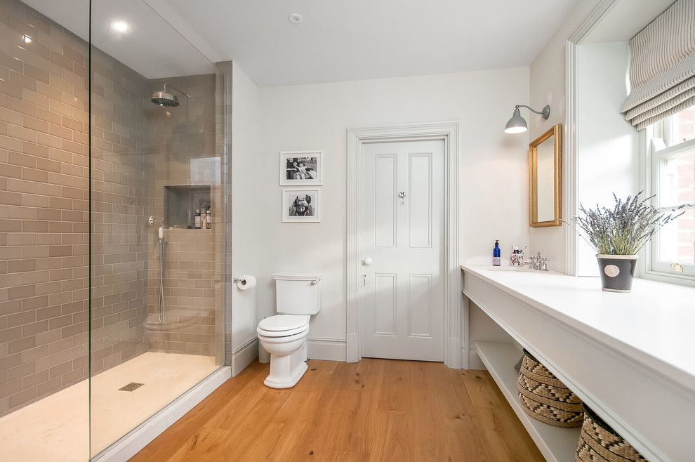 Inspiration for a large traditional family bathroom in Hampshire with freestanding cabinets, white cabinets, a walk-in shower, a two-piece toilet, brown tiles, ceramic tiles, white walls, medium hardwood flooring, a built-in sink, granite worktops, brown floors and an open shower.