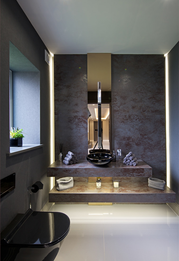 Exempel på ett mellanstort modernt en-suite badrum, med en vägghängd toalettstol, grå kakel, kakel i metall, grå väggar, klinkergolv i porslin, ett piedestal handfat och bänkskiva i akrylsten