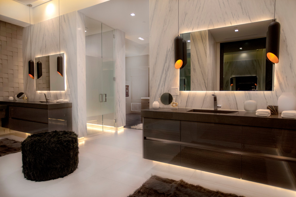 Example of a large minimalist master white tile and marble tile porcelain tile and white floor bathroom design in Los Angeles with flat-panel cabinets, dark wood cabinets, a one-piece toilet, white walls, an integrated sink, quartz countertops, a hinged shower door and black countertops