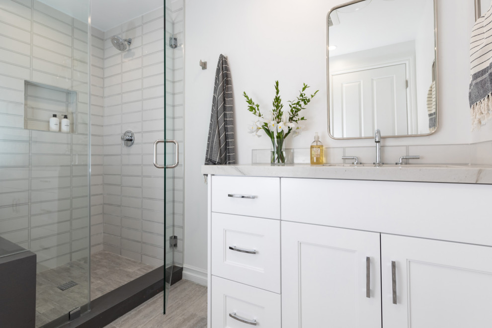 Medium sized beach style shower room bathroom in Los Angeles with shaker cabinets, white cabinets, a one-piece toilet, white tiles, ceramic tiles, white walls, ceramic flooring, a submerged sink, quartz worktops, grey floors, grey worktops, a shower bench, a single sink and a built in vanity unit.