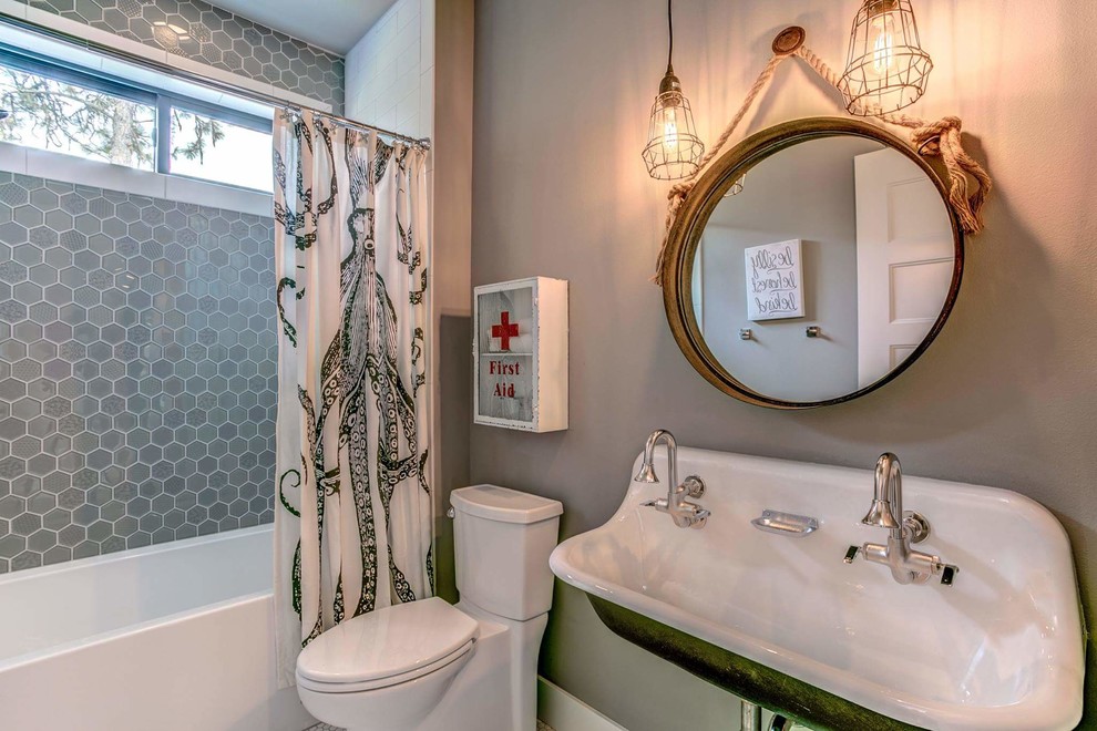 Exempel på ett mellanstort lantligt badrum för barn, med ett platsbyggt badkar, en toalettstol med hel cisternkåpa, grå kakel, glaskakel, grå väggar, laminatgolv, ett väggmonterat handfat, grått golv och dusch med duschdraperi