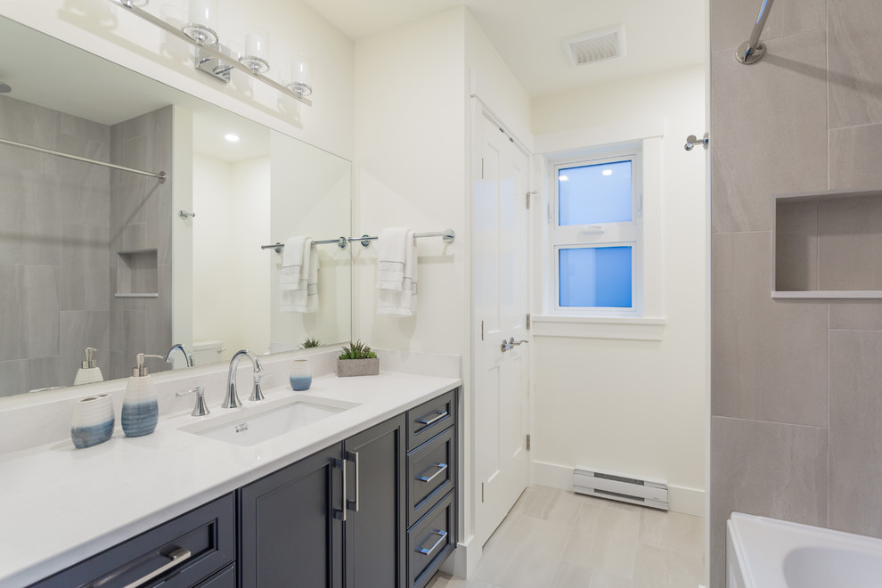 Example of a small transitional master gray tile and porcelain tile porcelain tile and gray floor alcove bathtub design in Vancouver with beaded inset cabinets, blue cabinets, a one-piece toilet, white walls, a wall-mount sink and quartz countertops