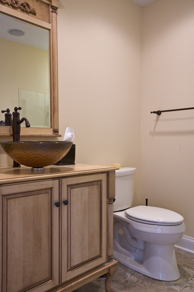 Cette image montre une petite salle de bain chalet en bois brun avec une vasque, un placard avec porte à panneau surélevé, un plan de toilette en bois, WC séparés, un carrelage beige, des carreaux de porcelaine, un mur beige et un sol en carrelage de porcelaine.