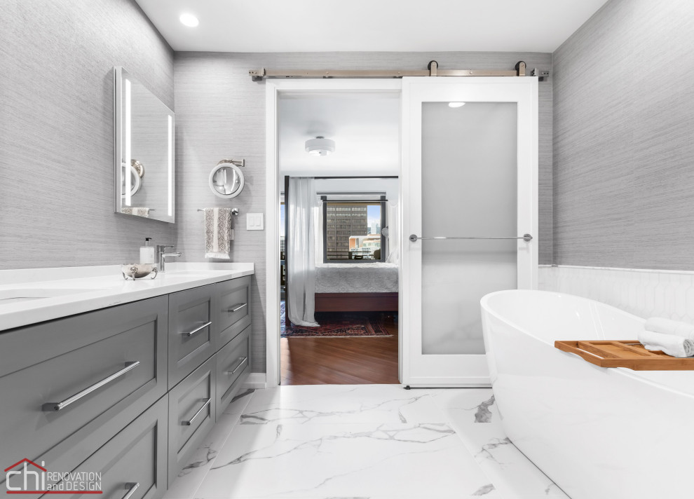 Cette image montre une grande salle de bain principale design avec des portes de placard noires, une baignoire indépendante, WC à poser, un carrelage gris, des carreaux de béton, un mur gris, un sol en marbre, un lavabo encastré, un plan de toilette en quartz modifié, un sol blanc, un plan de toilette blanc, meuble double vasque et meuble-lavabo encastré.