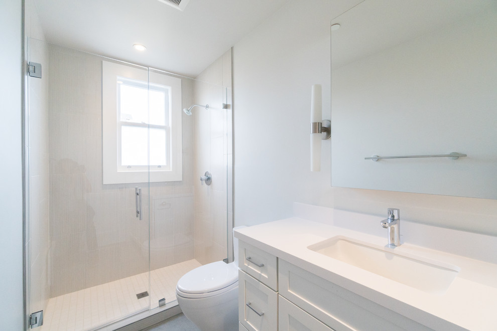 Пример оригинального дизайна: ванная комната среднего размера в стиле неоклассика (современная классика) с белыми фасадами, душем в нише, унитазом-моноблоком, белой плиткой, керамической плиткой, серыми стенами, полом из керамической плитки, врезной раковиной, столешницей из искусственного кварца, серым полом, душем с распашными дверями, фасадами в стиле шейкер и душевой кабиной