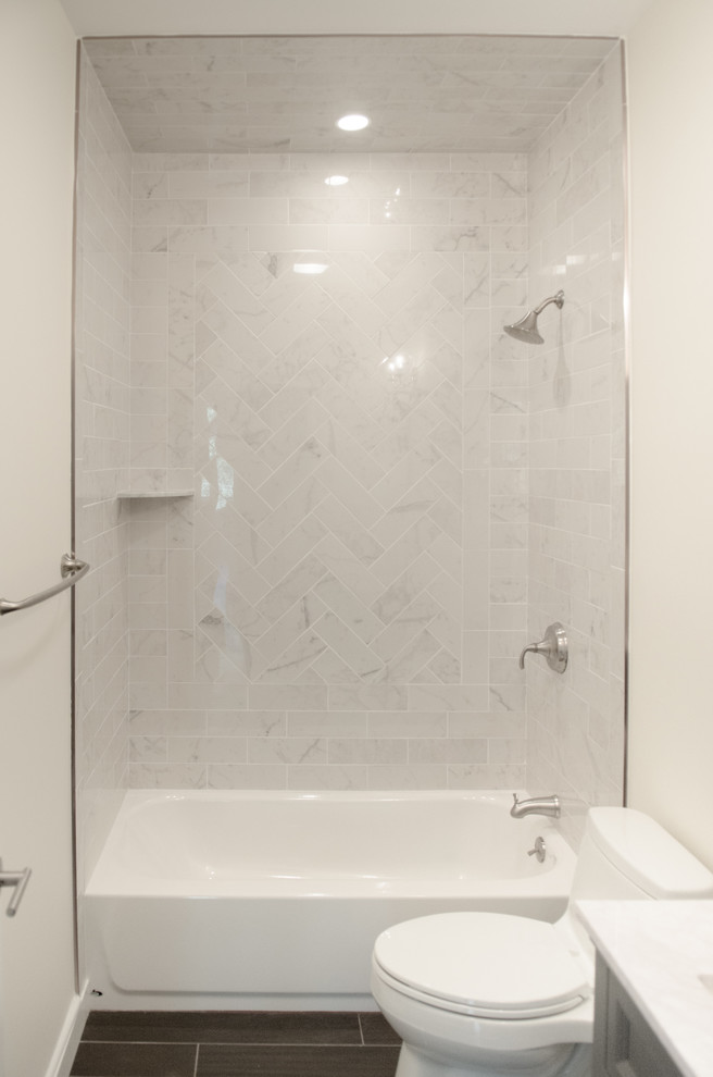 Cette photo montre une salle de bain chic de taille moyenne avec un placard à porte shaker, des portes de placard grises, une baignoire en alcôve, un combiné douche/baignoire, WC à poser, un carrelage blanc, du carrelage en marbre, un mur blanc, un sol en carrelage de porcelaine, un plan vasque, un plan de toilette en quartz modifié, un sol marron et une cabine de douche avec un rideau.