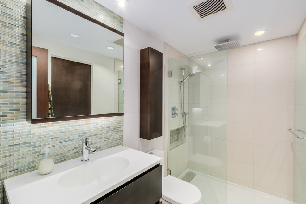 Kleines Modernes Duschbad mit flächenbündigen Schrankfronten, dunklen Holzschränken, Toilette mit Aufsatzspülkasten, farbigen Fliesen, Glasfliesen, weißer Wandfarbe, Porzellan-Bodenfliesen, integriertem Waschbecken und Mineralwerkstoff-Waschtisch in Vancouver