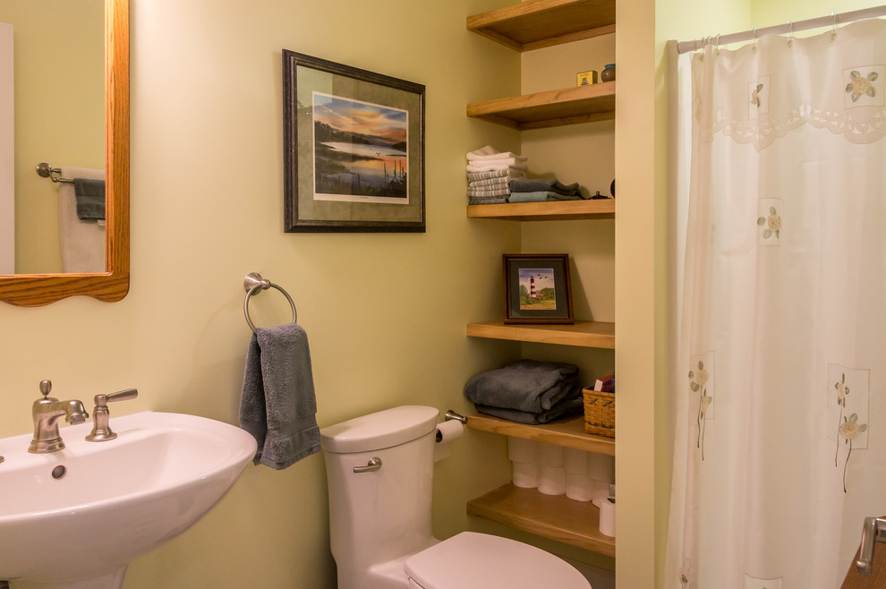 Modelo de cuarto de baño de estilo de casa de campo pequeño con ducha empotrada, sanitario de una pieza, paredes beige, aseo y ducha, lavabo con pedestal y ducha con cortina