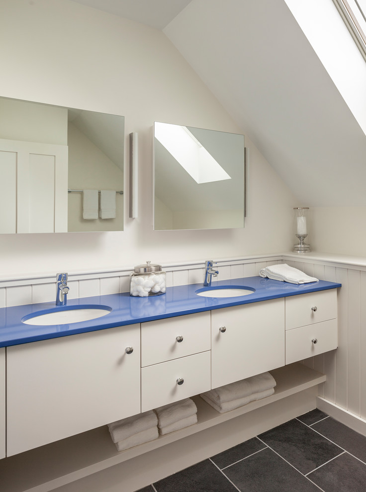 Ejemplo de cuarto de baño tradicional renovado con armarios con paneles lisos, puertas de armario blancas, paredes blancas, lavabo bajoencimera, suelo negro y encimeras azules