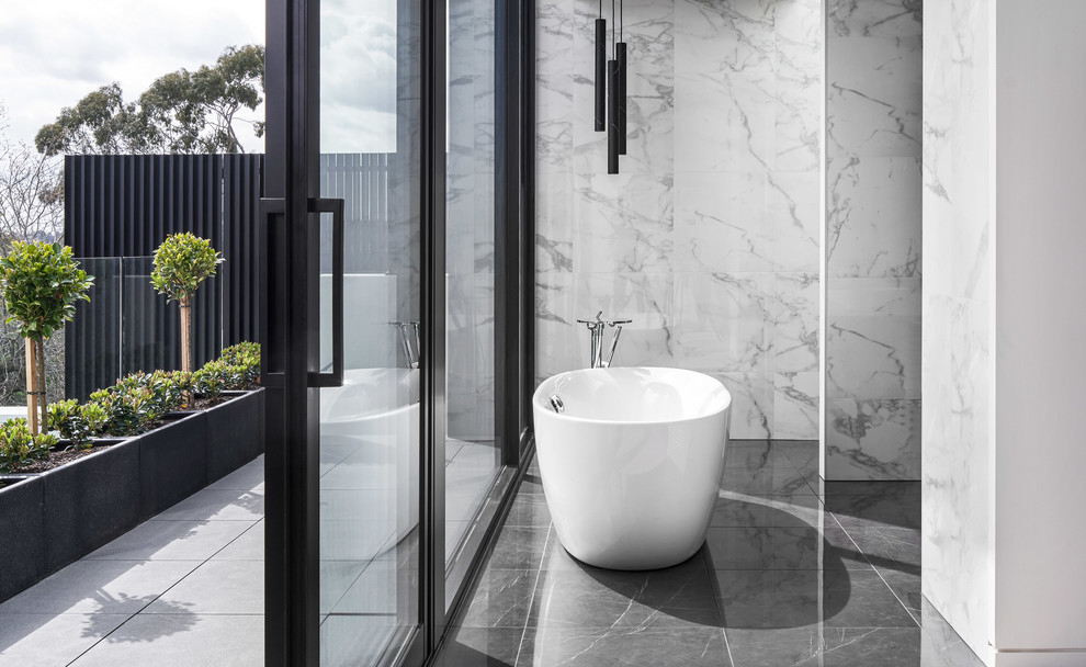 Design ideas for a large contemporary ensuite bathroom in Melbourne with recessed-panel cabinets, dark wood cabinets, a freestanding bath, a walk-in shower, a wall mounted toilet, white tiles, marble tiles, white walls, porcelain flooring, a console sink, marble worktops, grey floors, an open shower and white worktops.
