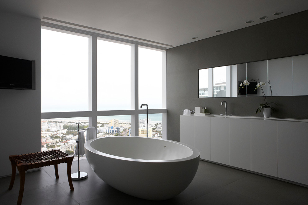 Immagine di una stanza da bagno moderna con ante lisce, ante bianche e vasca freestanding