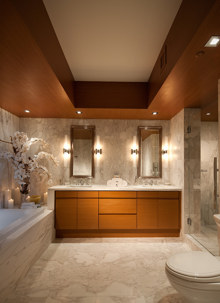 Example of a trendy gray tile drop-in bathtub design in Miami with flat-panel cabinets and medium tone wood cabinets