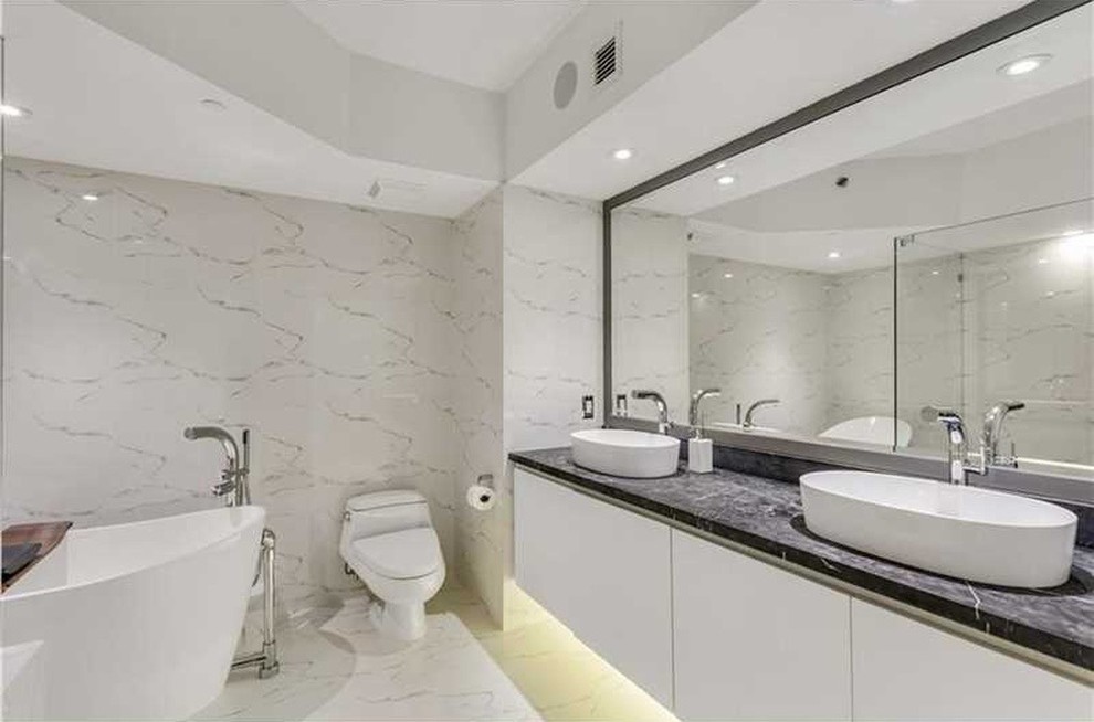 This is an example of a large contemporary ensuite bathroom in Miami with flat-panel cabinets, white cabinets, a freestanding bath, an alcove shower, a one-piece toilet, white walls and a vessel sink.