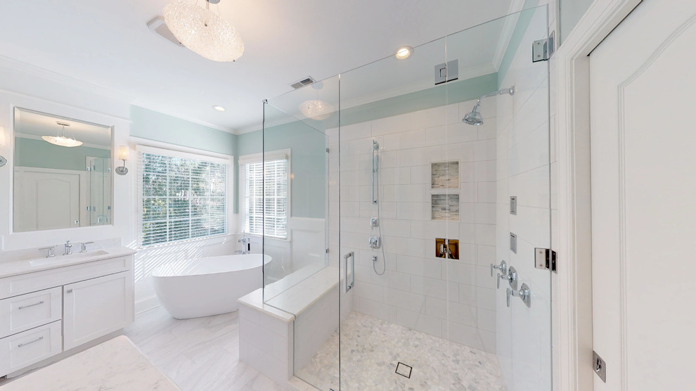 Идея дизайна: большая главная ванная комната в стиле неоклассика (современная классика) с фасадами в стиле шейкер, белыми фасадами, отдельно стоящей ванной, угловым душем, раздельным унитазом, белой плиткой, керамогранитной плиткой, синими стенами, полом из керамогранита, врезной раковиной, столешницей из искусственного кварца, серым полом, душем с распашными дверями, белой столешницей, тумбой под две раковины и встроенной тумбой