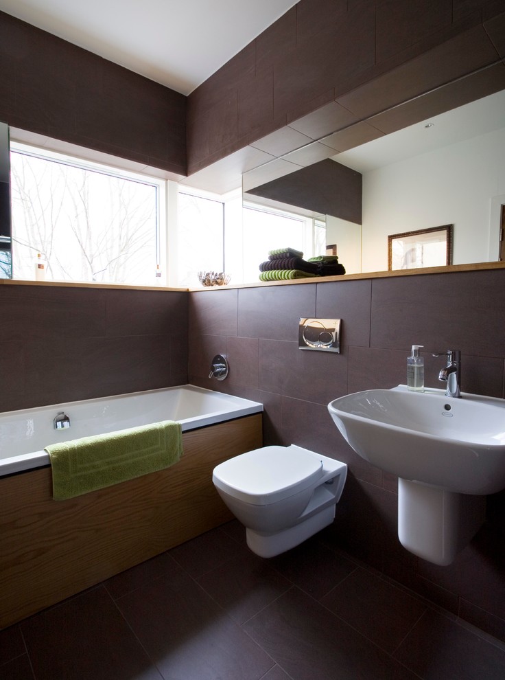 Idéer för att renovera ett mellanstort funkis badrum, med ett väggmonterat handfat, skåp i mörkt trä, ett badkar i en alkov, en vägghängd toalettstol, brun kakel, porslinskakel, bruna väggar och klinkergolv i porslin