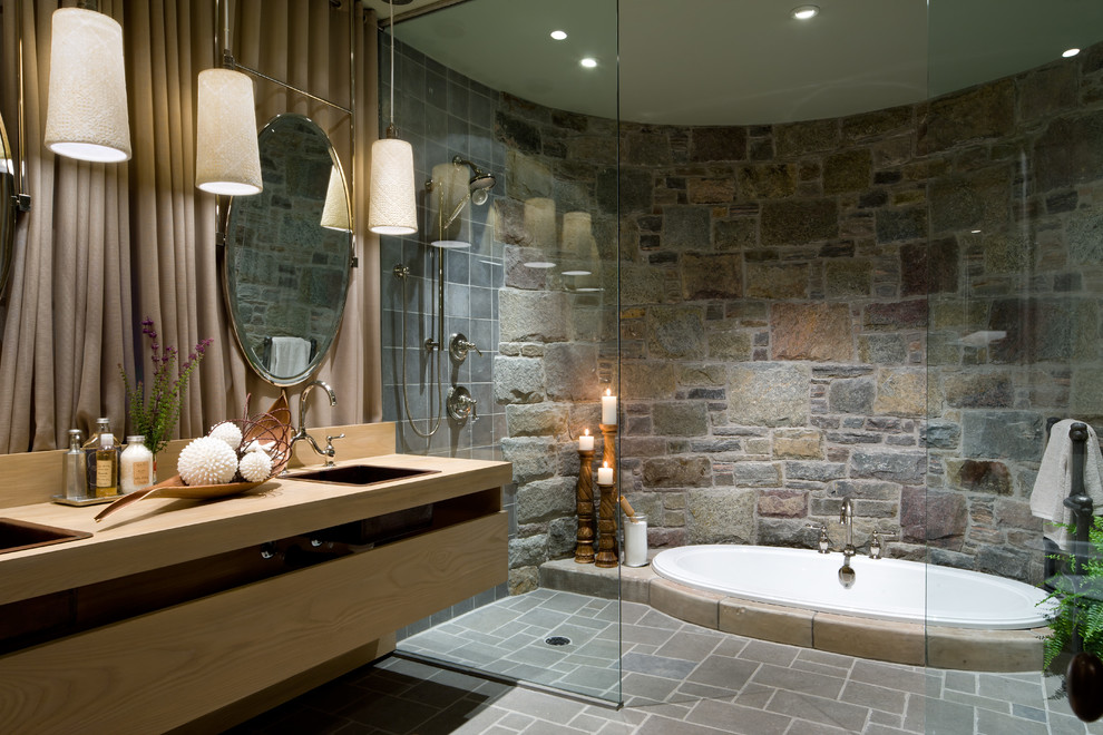 Cette photo montre une salle de bain chic avec un lavabo posé, une baignoire posée, un carrelage gris, une douche à l'italienne et un mur en pierre.