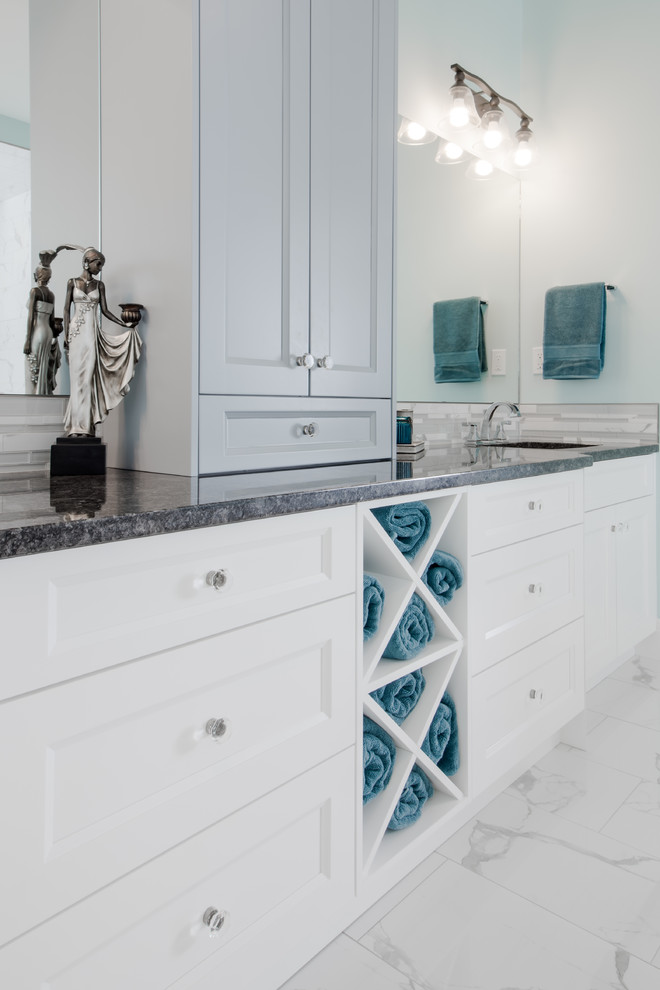 This is an example of an expansive classic ensuite bathroom in Calgary with shaker cabinets, white cabinets, a built-in bath, a walk-in shower, a two-piece toilet, white tiles, marble tiles, blue walls, marble flooring, a submerged sink and granite worktops.