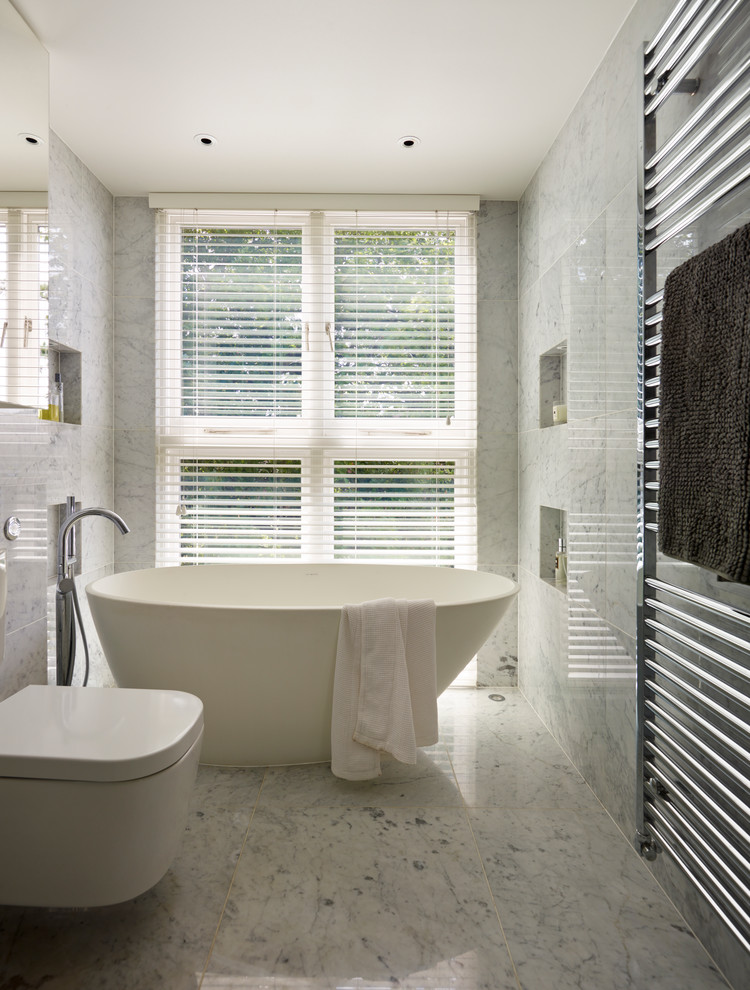 Inspiration for a contemporary gray tile and marble tile marble floor freestanding bathtub remodel in London with a wall-mount toilet and gray walls