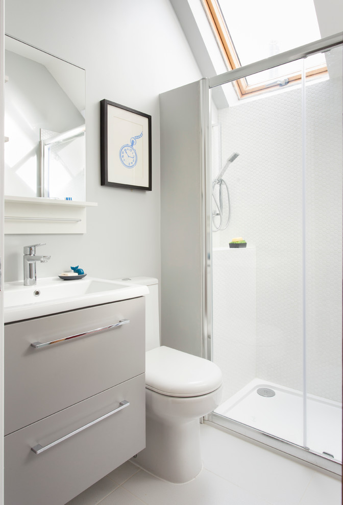 Diseño de cuarto de baño actual con armarios con paneles lisos, puertas de armario grises, ducha empotrada, baldosas y/o azulejos blancos, baldosas y/o azulejos en mosaico, paredes grises y lavabo encastrado