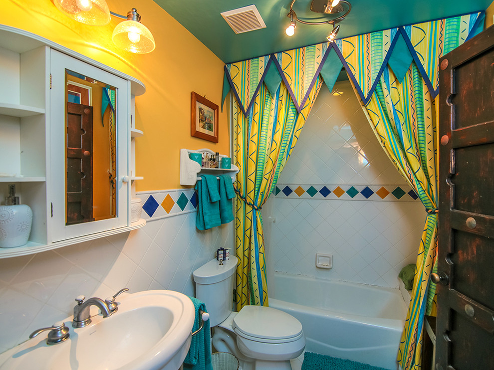 Kleines Eklektisches Badezimmer mit Badewanne in Nische, Duschbadewanne, Toilette mit Aufsatzspülkasten, weißen Fliesen, Porzellanfliesen, gelber Wandfarbe und Sockelwaschbecken in Miami