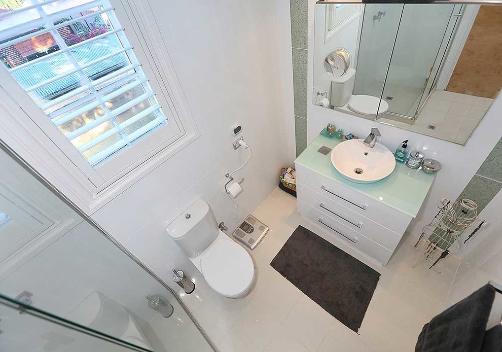 Inspiration för små moderna badrum med dusch, med ett fristående handfat, släta luckor, vita skåp, bänkskiva i glas, en hörndusch, en toalettstol med separat cisternkåpa, gul kakel och klinkergolv i keramik