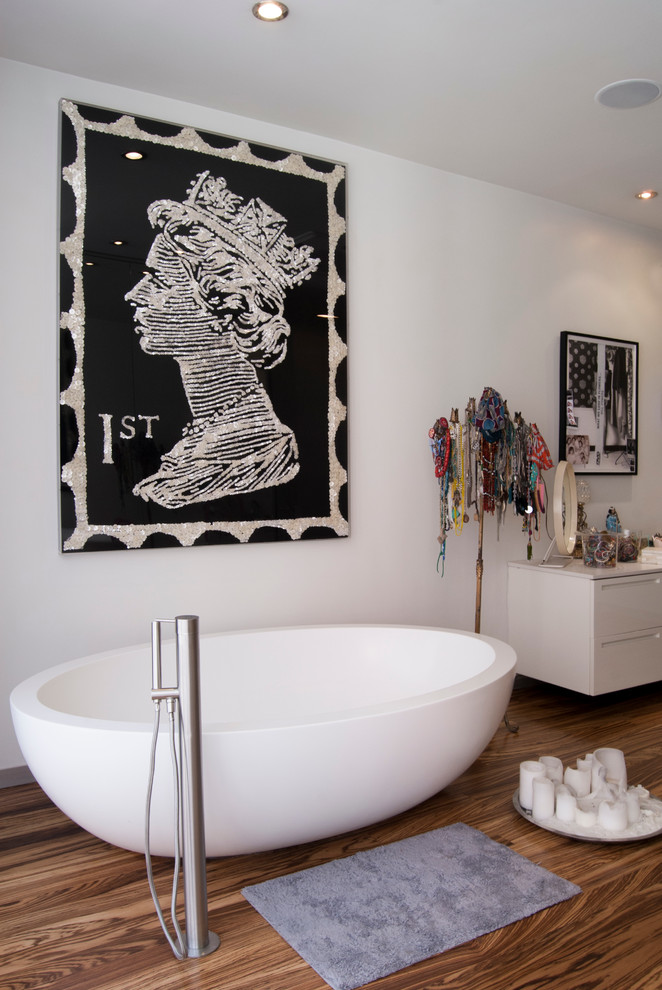 На фото: большая главная ванная комната в современном стиле с плоскими фасадами, белыми фасадами, столешницей из искусственного камня, отдельно стоящей ванной, белыми стенами и паркетным полом среднего тона с