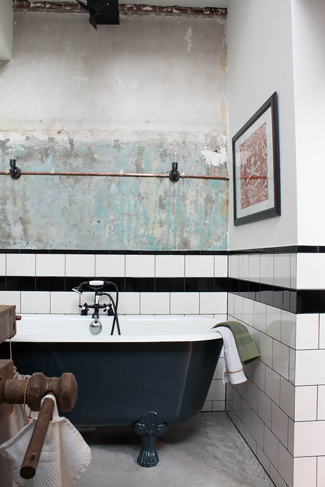 Exemple d'une salle de bain industrielle avec une baignoire sur pieds, un carrelage métro, un carrelage noir et blanc et du carrelage bicolore.