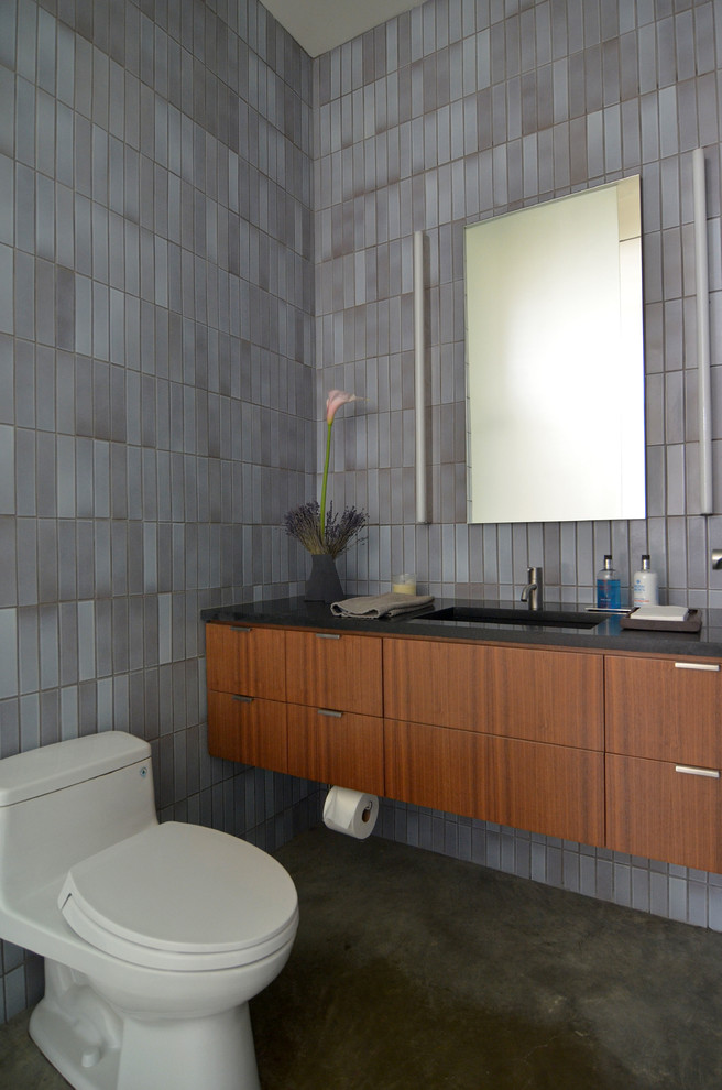 Idee per una stanza da bagno design con lavabo sottopiano, ante lisce, ante in legno scuro e piastrelle grigie