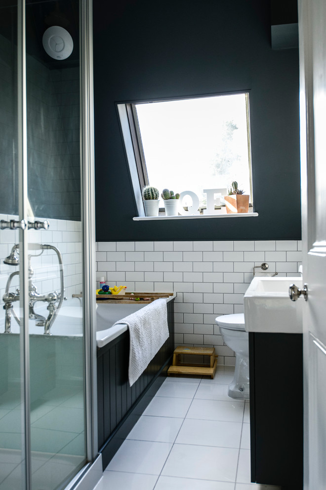Transitional drop-in bathtub photo in London with an integrated sink, black cabinets and black walls
