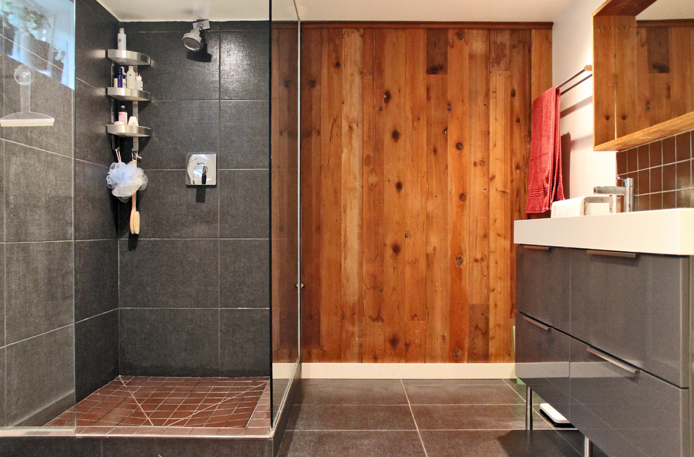 Stilmix Badezimmer mit flächenbündigen Schrankfronten, grauen Schränken, Eckdusche und grauen Fliesen in Montreal