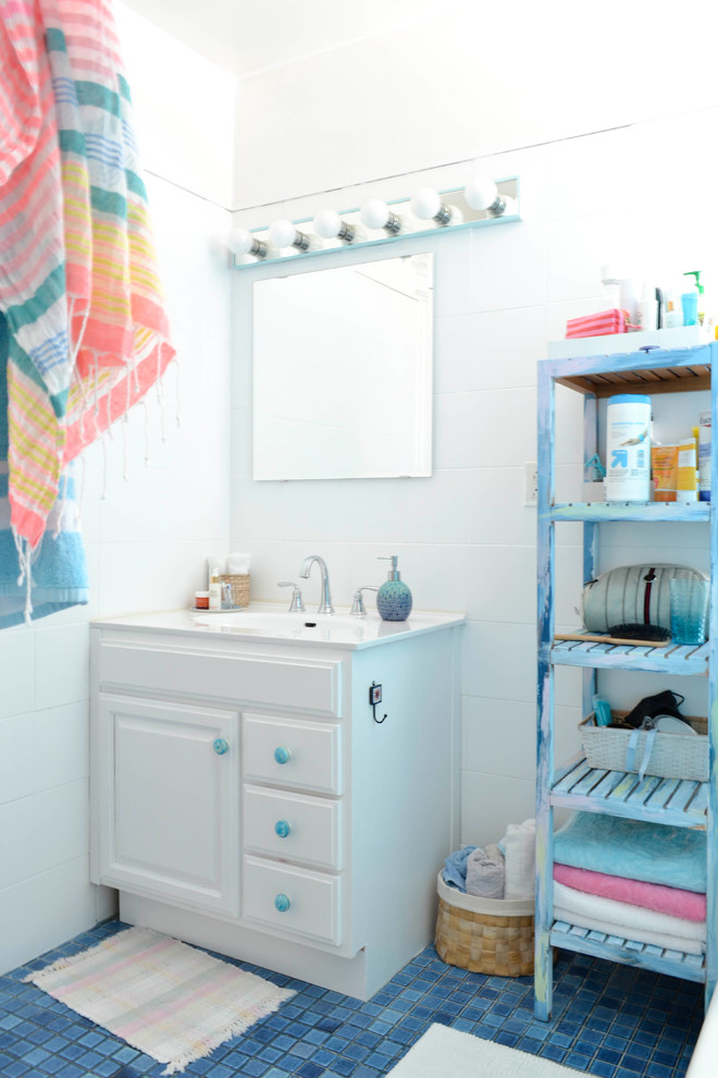 Réalisation d'une petite salle de bain bohème avec un placard avec porte à panneau surélevé, des portes de placard blanches, un carrelage blanc, un mur blanc, un sol en carrelage de terre cuite, un sol bleu et un plan de toilette blanc.