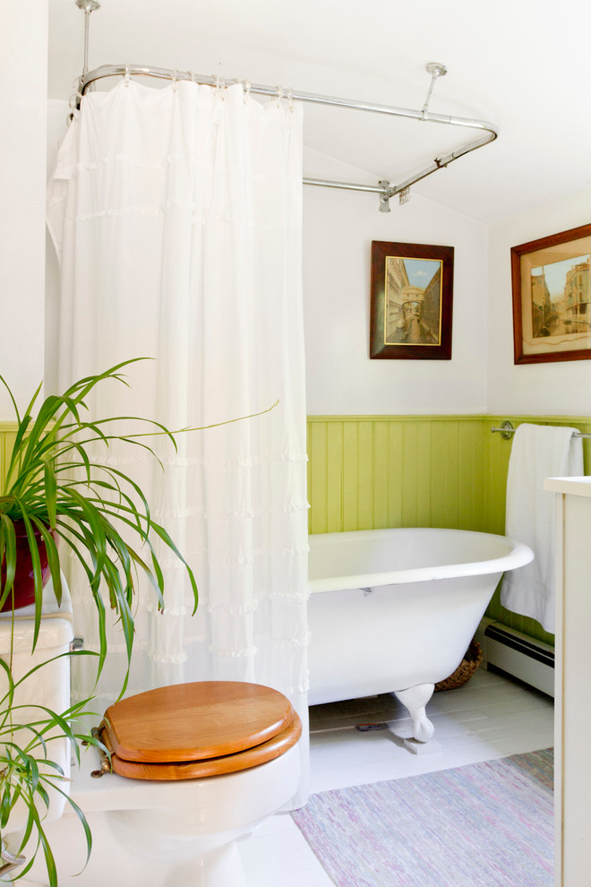 На фото: ванная комната в викторианском стиле с ванной на ножках, душем над ванной, раздельным унитазом, белыми стенами и деревянным полом с