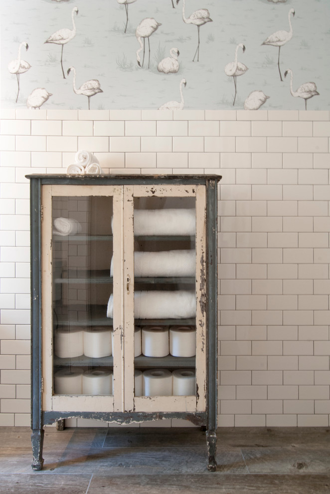 Eklektisk inredning av ett mellanstort badrum, med ett fristående handfat, skåp i slitet trä, marmorbänkskiva, en dusch i en alkov, vit kakel, tunnelbanekakel, vita väggar, klinkergolv i keramik och luckor med glaspanel