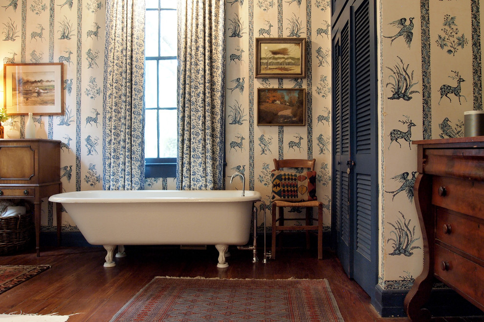 На фото: ванная комната в классическом стиле с ванной на ножках, темным паркетным полом и плоскими фасадами с