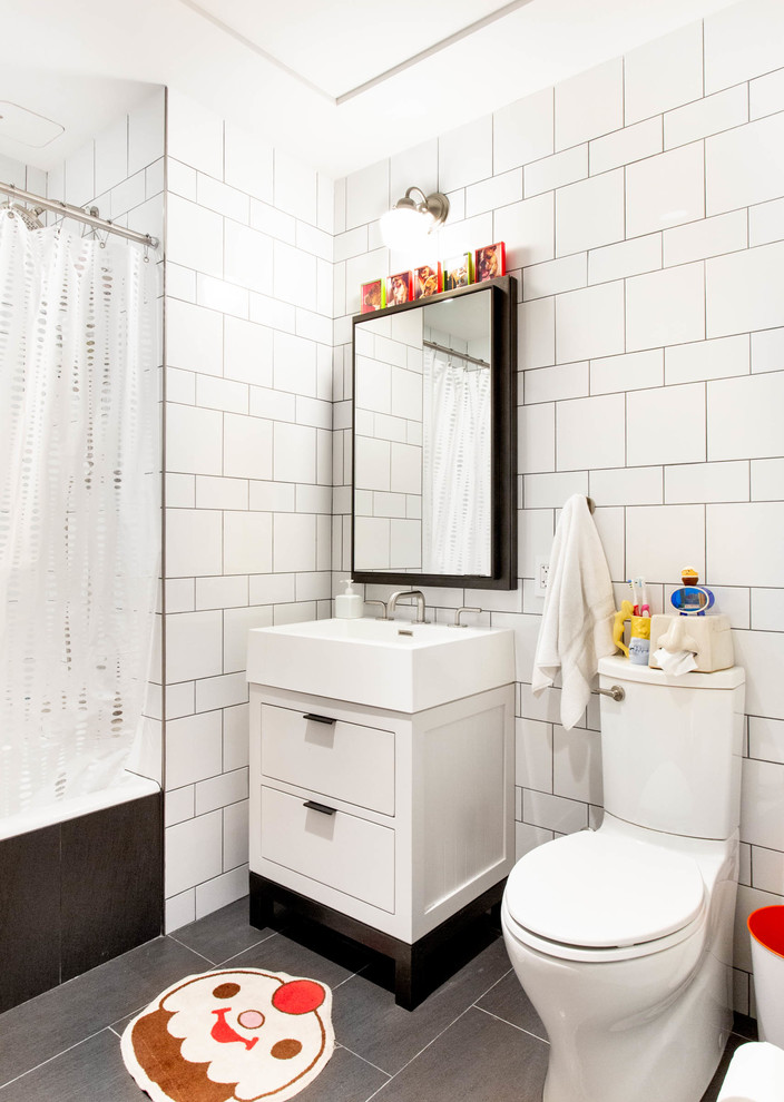 ニューヨークにあるエクレクティックスタイルのおしゃれな浴室 (フラットパネル扉のキャビネット、白いキャビネット、アルコーブ型浴槽、シャワー付き浴槽	、白いタイル、グレーの床、シャワーカーテン) の写真