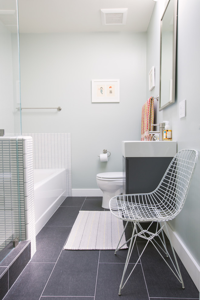 Imagen de cuarto de baño gris y blanco actual con lavabo tipo consola, armarios con paneles lisos, puertas de armario grises, bañera empotrada, baldosas y/o azulejos blancos, paredes grises y suelo gris