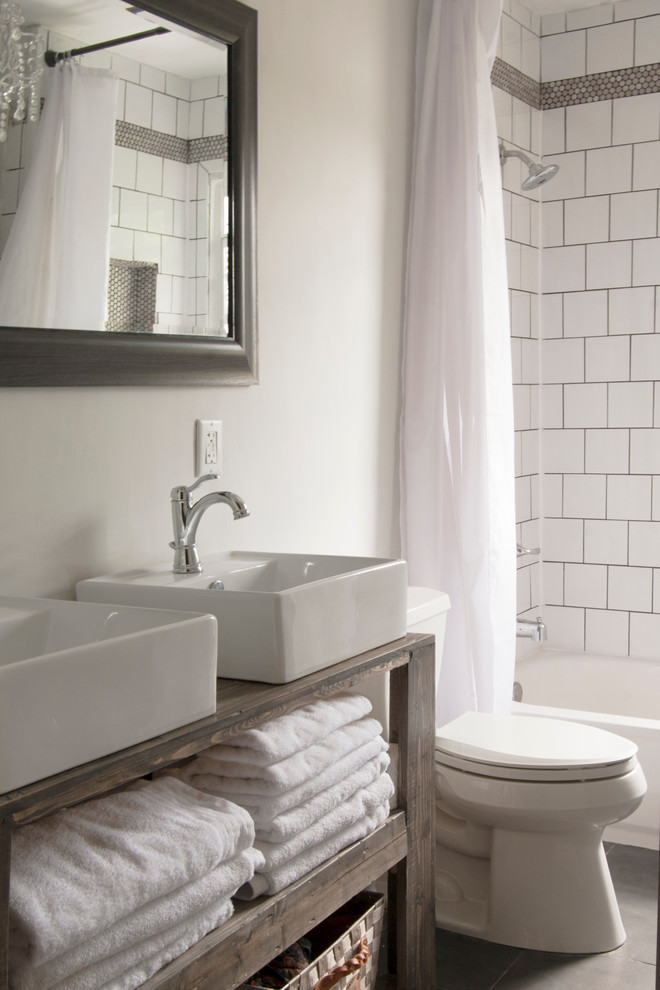 Idéer för att renovera ett litet shabby chic-inspirerat brun brunt en-suite badrum, med ett fristående handfat, öppna hyllor, skåp i mellenmörkt trä, träbänkskiva, ett badkar i en alkov, en dusch/badkar-kombination, en toalettstol med separat cisternkåpa, vit kakel, keramikplattor, grå väggar och klinkergolv i keramik