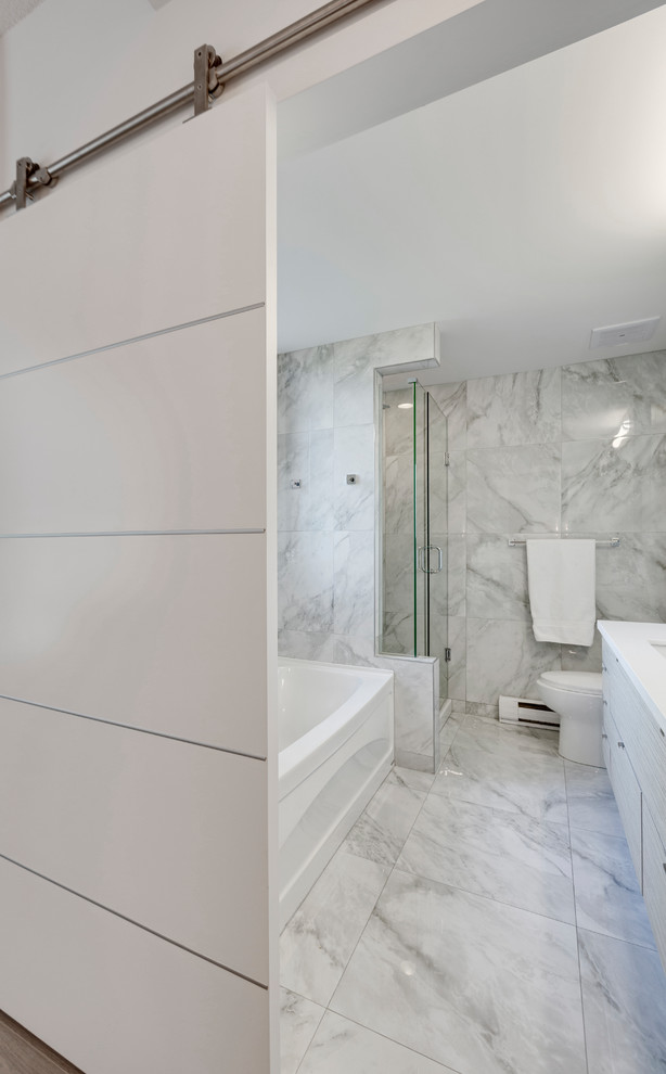 Modern inredning av ett litet vit vitt badrum med dusch, med släta luckor, grå skåp, en hörndusch, en toalettstol med hel cisternkåpa, grå kakel, porslinskakel, vita väggar, klinkergolv i porslin, ett integrerad handfat, bänkskiva i akrylsten, grått golv och dusch med gångjärnsdörr