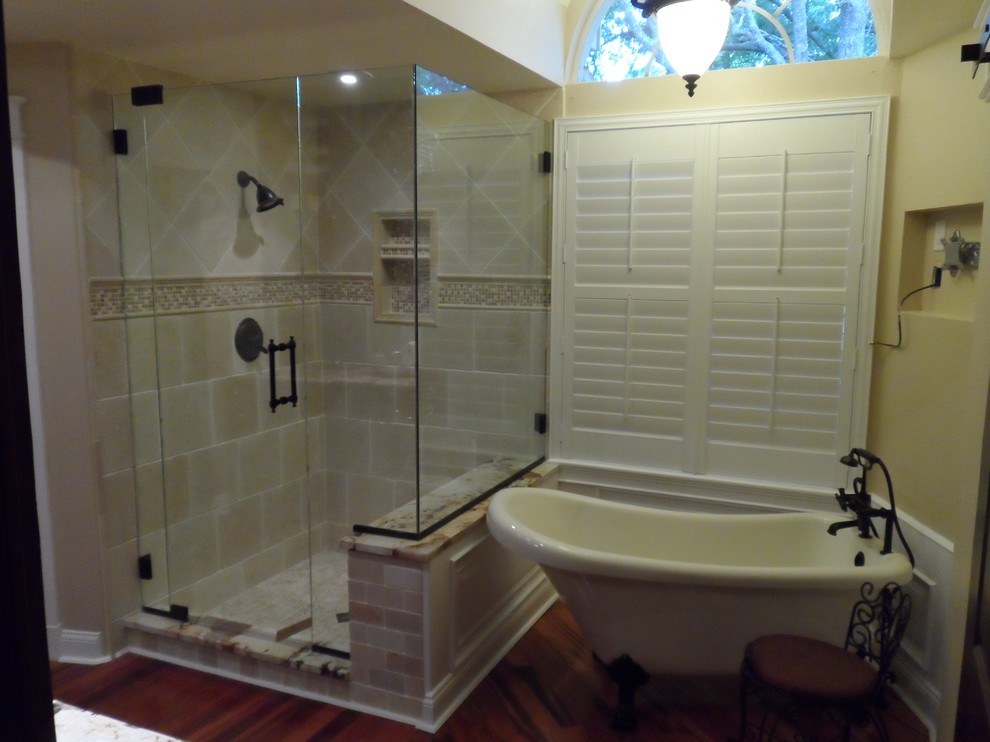 Imagen de cuarto de baño principal clásico de tamaño medio con bañera exenta, ducha empotrada, baldosas y/o azulejos beige, baldosas y/o azulejos de piedra, paredes beige y suelo de madera en tonos medios