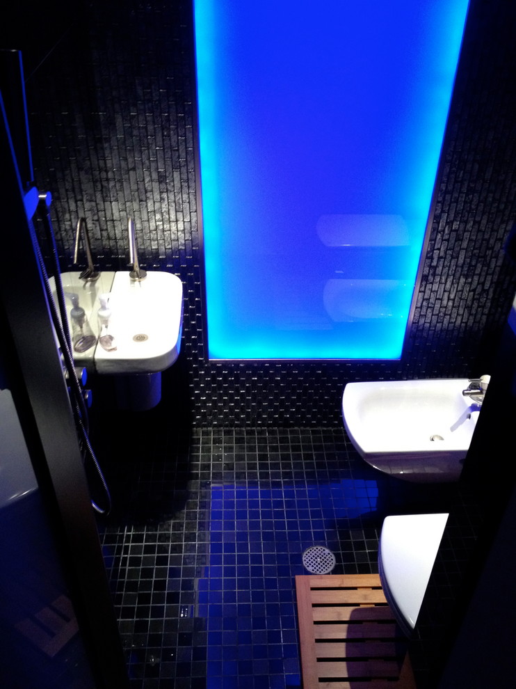 Ejemplo de cuarto de baño moderno pequeño con lavabo suspendido, combinación de ducha y bañera, sanitario de pared, baldosas y/o azulejos negros, baldosas y/o azulejos de vidrio, paredes negras y aseo y ducha