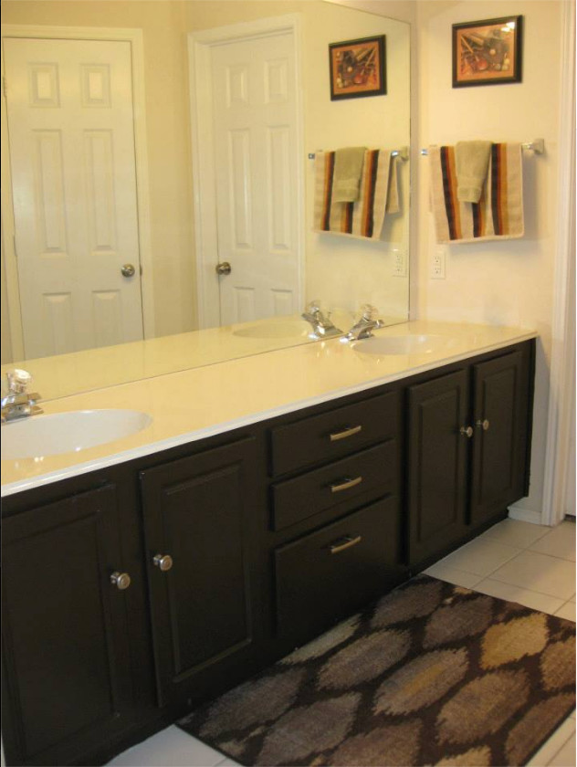 Ispirazione per una stanza da bagno padronale chic di medie dimensioni con ante con bugna sagomata, ante nere, pareti gialle, pavimento con piastrelle in ceramica, lavabo integrato e top in marmo