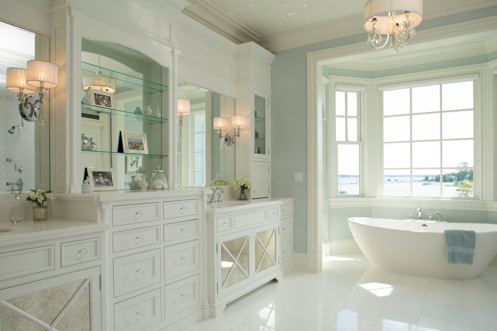 Modelo de cuarto de baño principal y rectangular clásico con puertas de armario blancas, bañera exenta, paredes azules y armarios con paneles empotrados